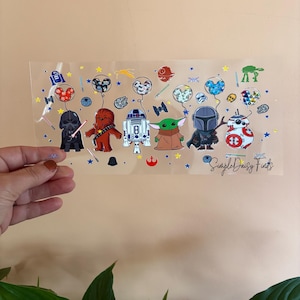 May include: A clear sheet of vinyl with a variety of Star Wars characters and Mickey Mouse. The characters are holding balloons with Mickey Mouse heads on them. The sheet also has stars and other space-themed designs. The text "Simple Daisy Finds" is at the bottom of the sheet.