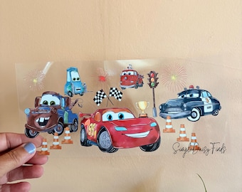 May include: A clear sheet featuring cartoon car characters, including a red race car with the number 95, a brown tow truck, and a blue car. The sheet also includes traffic cones, checkered flags, and a trophy. The text "Simple Daisy Finds" is visible.