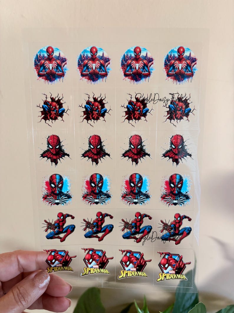 May include: A sheet of clear stickers featuring various images of Spider-Man. The stickers showcase Spider-Man in different poses and designs, with vibrant red, blue, and black colours. Some stickers include the text "Spider-Man".