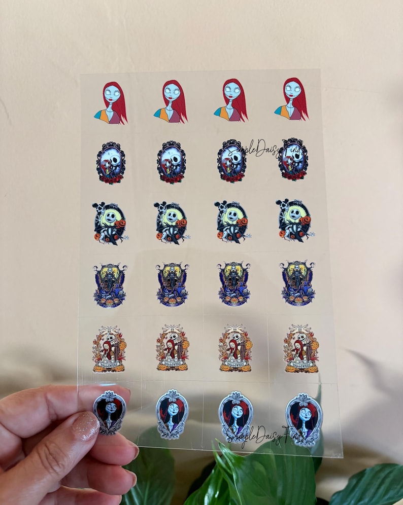 Puede incluir: Hoja transparente de pegatinas con personajes de Pesadilla antes de Navidad. Las pegatinas incluyen im&aacute;genes de Sally, Jack Skellington y otros personajes en varios dise&ntilde;os, con un tema floral y g&oacute;tico.