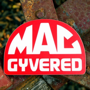 May include: A red and white sticker with the text "MAC GYVERED" in white letters on a red background.