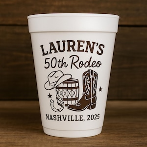 May include: A white foam cup with a brown graphic design. The design includes a cowboy hat, barrel, boot, horseshoe, and stars. Text on the cup reads "LAUREN'S 50th Rodeo" and "NASHVILLE, 2025".
