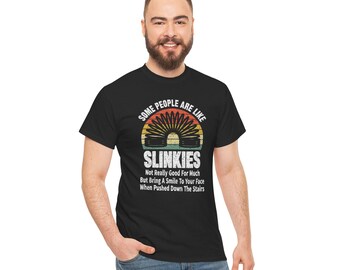 May include: A black t-shirt with a vintage-style graphic of a slinky toy. The text reads "Some people are like Slinkies. Not really good for much but bring a smile to your face when pushed down the stairs."
