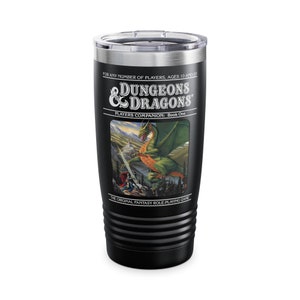Puede incluir: Vaso térmico negro con el logo "Dungeons & Dragons" y una ilustración de fantasía de un dragón. El texto incluye "Players Companion: Book One" y "The Original Fantasy Role-Playing Game."
