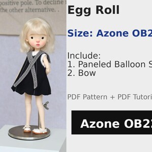 May include: A doll in a black dress with a white and black striped detail. The doll has blonde hair and is on a silver stand. The image includes the text "Egg Roll" and "Azone OB22".