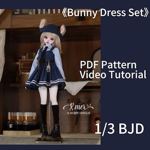 Op de afbeelding: Een blauwe en witte konijnenjurk set voor een 1/3 BJD pop. De jurk heeft een witte kraag, een blauw-witte gestreepte zoom en een riem met een sleutelgat detail. De set bevat een PDF-patroon en een video tutorial.  "Bunny Dress Set" en "1/3 BJD" staan in de afbeelding.