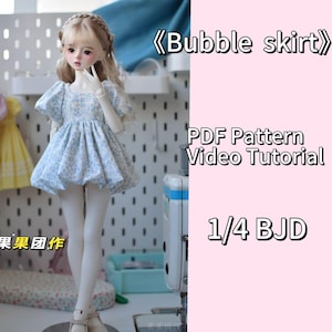 Puede incluir: Una muñeca con una falda de burbuja floral azul y blanca con mangas abullonadas. La muñeca está de pie frente a una máquina de coser. El texto "Bubble skirt" está escrito en rosa sobre un fondo rosa. El texto "PDF Pattern Video Tutorial 1/4 BJD" también está escrito en rosa sobre un fondo rosa.