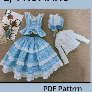 Puede incluir: Un vestido azul y blanco con ribete de encaje blanco y un gorro a juego. El vestido tiene un corpiño blanco con un lazo y una falda azul con volantes blancos. El vestido es para una muñeca a escala 1/4. La imagen también incluye una blusa blanca con ribete de encaje. El texto "1/4 KUMAKO PDF Pattrrn Video Tutorial" está en la parte superior de la imagen.