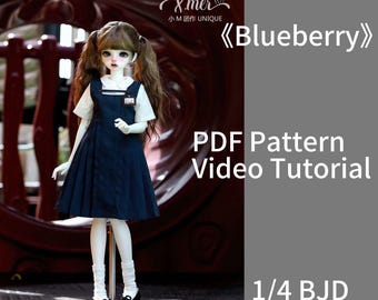 Pode incluir: Uma boneca BJD de 1/4 usando um traje azul e branco com um colarinho branco e uma etiqueta com o nome "B.A.K." A boneca tem cabelo castanho longo e está em pé em um suporte branco. A imagem inclui o texto "&mer 小M团作 UNIQUE 《Blueberry》 PDF Pattern Video Tutorial 1/4 BJD".
