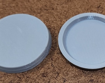 May include: Two gray plastic round lids, one with a smooth top and the other with a slightly raised rim.