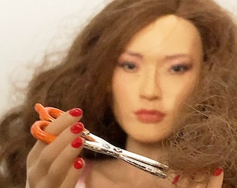 May include: A woman with long brown hair is holding a pair of silver scissors with orange handles. She is cutting her hair with the scissors.
