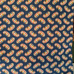 Puede incluir: Tela azul marino con un estampado de cachemir repetido. El diseño de cachemir presenta elementos florales rojos, naranjas, amarillos y azules. La tela tiene un aspecto texturizado, ideal para acolchar o manualidades.