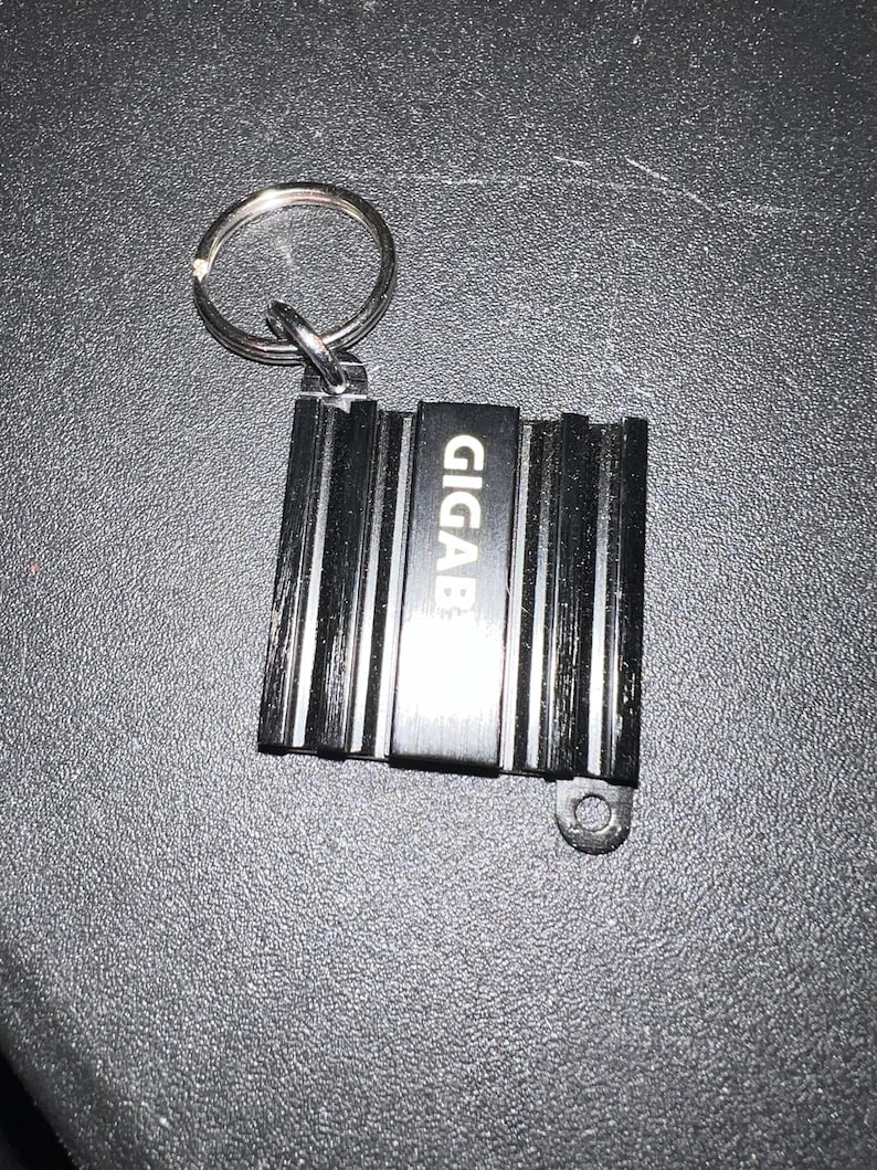 May include: Black metal keychain with a silver ring and the word "GIGAB" engraved on the front.