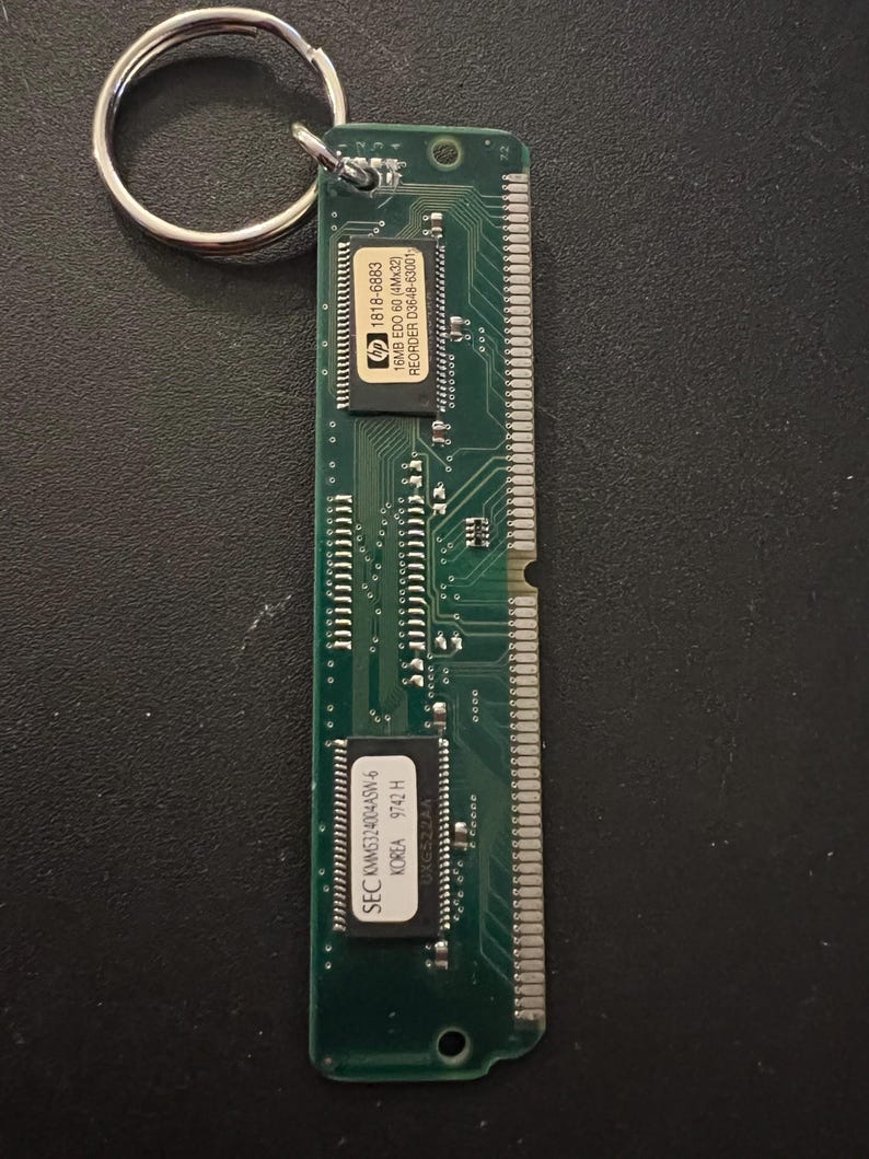 May include: A green circuit board keychain with a silver key ring. The circuit board has text that reads "hp 1818-6883 16MB EDO 60 (4Mx32) REORDER D3648-63001" and "SEC KMM5324004ASW-6 KOREA 9742 H".