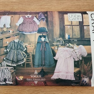 Könnte beinhalten: Ein Vintage-Puppenkleidungs-Schnittmuster von Vogue Craft mit fünf verschiedenen Outfits für eine Puppe. Das Schnittmuster beinhaltet ein Kleid, einen Umhang, eine Mütze, ein Kleid mit Rüschen und eine Hose. Das Schnittmuster wurde von Linda Carr entworfen und ist für eine Größe.