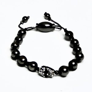 May include: A black beaded bracelet with a skull charm and a black cord with a toggle clasp.