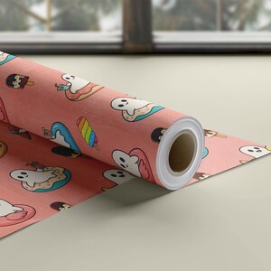 May include: A roll of wrapping paper with a salmon-pink background featuring a repeating pattern of white cartoon ghosts, colorful rainbow popsicles, chocolate-dipped ice cream bars, and ghosts floating in pink flamingo pool floats.