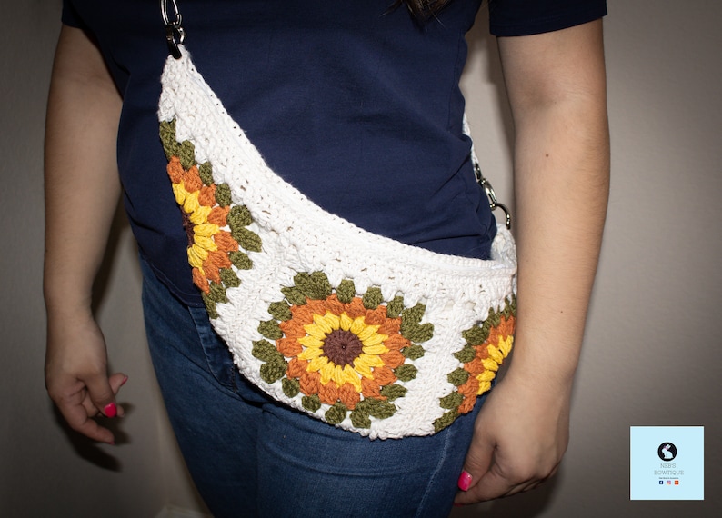May include: A white crocheted bag with a sunflower design. The bag has a long strap and is worn across the body.