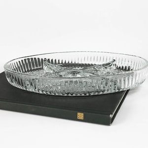 May include: A clear glass serving dish with four sections. The dish has a textured, ribbed design and is sitting on a black surface.
