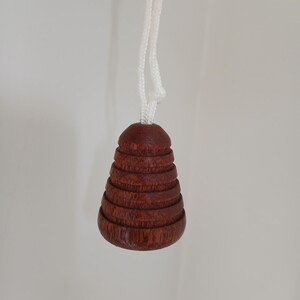 Peut inclure: Un tirette de lumi&egrave;re en bois brun fonc&eacute; avec un cordon blanc. La tirette a la forme d'un c&ocirc;ne empil&eacute;, avec plusieurs anneaux distincts. Le cordon est nou&eacute; en haut.