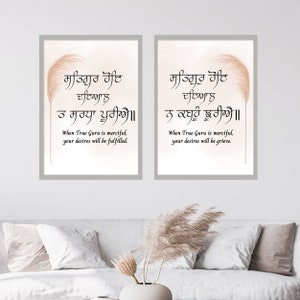 May include: Two framed prints with a white background and a light brown feather design. The prints feature a quote in the Gurmukhi script, the Punjabi language, with an English translation below. The quote is "Satguru hoay dayaalu, ta saradha pooriay" which translates to "When True Guru is merciful, your desires will be fulfilled." The second print features the quote "Satguru hoay dayaalu, na kabahu jhooriay" which translates to "When True Guru is merciful, your desires will be grieved."
