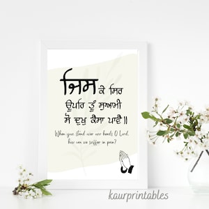 May include: A black and white printable wall art design with a Punjabi quote in Gurmukhi script that reads "श्रिम के मिठ ਊਪਰਿ ਤੂੰ ਸੁਆਮੀ ਸੋ ਦੁਖੁ ਕੈਸਾ ਪਾਵੈ॥" and the English translation "When you stand over our hands O Lord, how can we suffer in pain?" The design also includes a pair of praying hands.