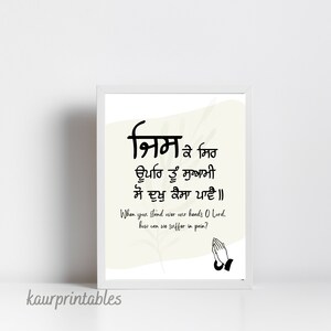 May include: A printable wall art design featuring a Punjabi prayer in black text on a white background with a light beige watercolor wash. The prayer reads "निम के मिठ ਊਪਰਿ ਤੂੰ ਸੁਆਮੀ ਸੋ ਦੁਖੁ ਕੈਸਾ ਪਾਵੈ॥" and translates to "When you stand over our hands O Lord, how can we suffer in pain?" The design also includes a black illustration of two hands clasped in prayer.