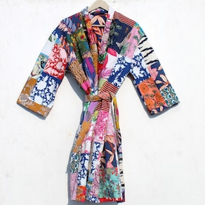 May include: A colorful patchwork robe with a floral and geometric print. The robe has a long, flowing silhouette and a tie belt.