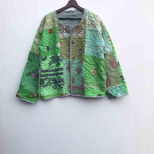 May include: A patchwork jacket in shades of green, featuring various patterns and textures. The jacket has a round neckline, long sleeves, and a striped lining. It is embellished with embroidery and sequins, and is approximately 25 inches in length.