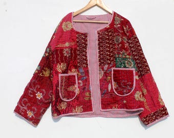 May include: A red quilted jacket with floral embroidery and patchwork design. The jacket features two front pockets and a striped lining. It is displayed on a wooden hanger against a white background.