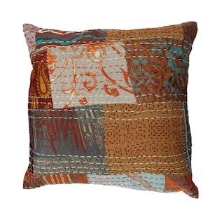 May include: A square patchwork pillow with a variety of colors and patterns, including brown, orange, gray, and blue. The pillow is made of fabric and has a quilted design.