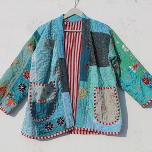 May include: A blue, green and red patchwork jacket with a striped lining. The jacket has two pockets and is made of a soft, quilted fabric.