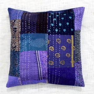 May include: A patchwork pillow cover with a variety of purple and blue fabrics. The cover is made of a variety of different fabrics, including silk and cotton. The cover is quilted and has a unique design.