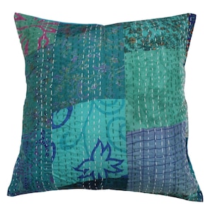 May include: A patchwork pillow cover with a blue and green color scheme. The cover is made of different fabrics with floral and geometric patterns. The pillow cover is stitched with white thread.