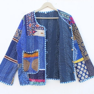 May include: A blue patchwork quilted jacket with a button closure and a pocket on the left side. The jacket has a white and blue checkered trim around the edges.