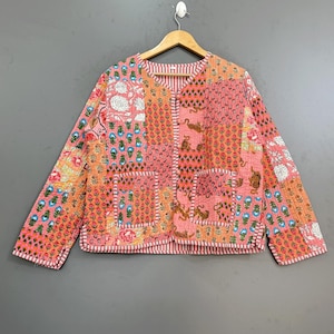 May include: A long-sleeve quilted jacket featuring a patchwork design with various floral and animal prints in shades of pink, orange, and blue. The jacket has a V-neckline, a front button closure, two front pockets, and red and white striped trim.