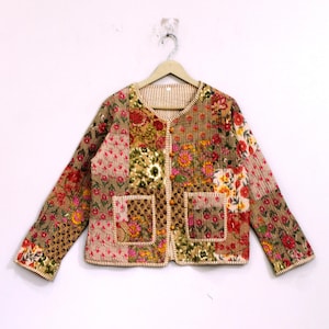 Könnte beinhalten: Eine langärmelige Steppjacke mit Patchwork-Design und verschiedenen Blumenmustern in Braun-, Rosa-, Rot- und Gelbtönen. Die Jacke hat einen Rundhalsausschnitt, eine Knopfleiste an der Vorderseite mit kleinen runden Knöpfen und zwei quadratische Taschen.