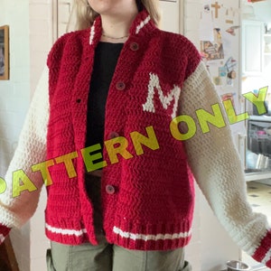 Puede incluir: Chaqueta de béisbol de punto de ganchillo rojo y blanco con una letra "M" blanca en la parte delantera. Las mangas son blancas con rayas rojas en los puños.