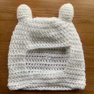 May include: White crocheted hat with ear flaps, resembling a bear's head.