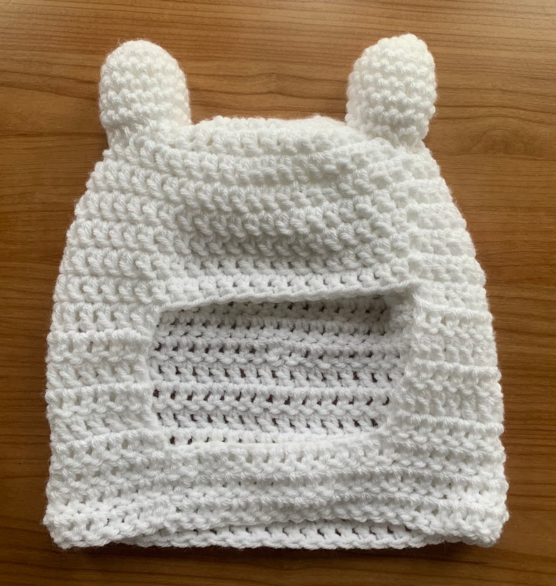 May include: White crocheted hat with ear flaps, resembling a bear's head.