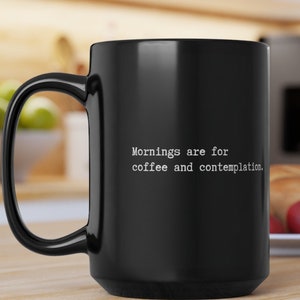 May include: Black coffee mug with white text that reads "Mornings are for coffee and contemplation."