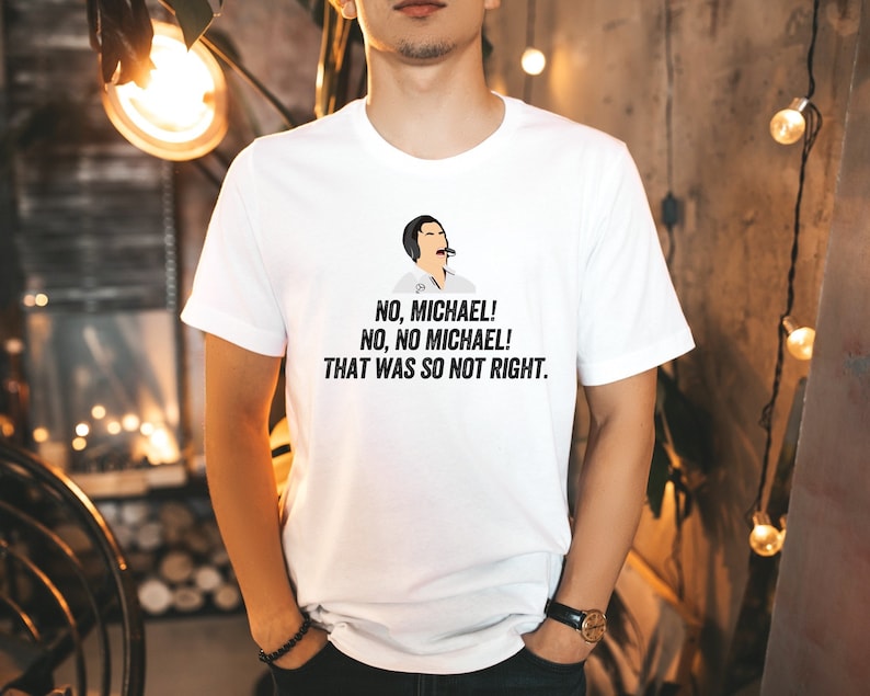 Może przedstawiać: Biała koszulka z czarno-białym rysunkiem osoby z mikrofonem i tekstem "NO, MICHAEL! NO, NO MICHAEL! THAT WAS SO NOT RIGHT."