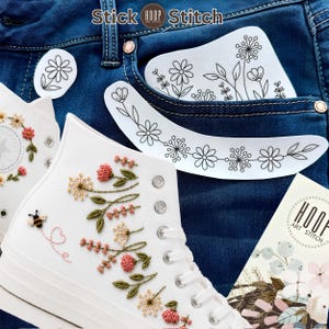Op de afbeelding: Witte hoge sneakers met geborduurde bloemmotieven en een kleine bij met een gestikt hartjesspoor. Inclusief witte zelfklevende patches met zwarte lijntekeningen van bloemen en een kaart met het label Stick Hoop Stitch.