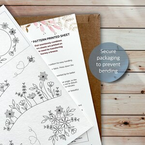 Puede incluir: Una hoja de papel blanca con patrones de bordado de l&iacute;neas negras de flores, hojas y una abeja, junto a una hoja de instrucciones con el texto 'PATTERN PRINTED SHEET' y un sobre marr&oacute;n con el texto 'Secure packaging to prevent bending'.