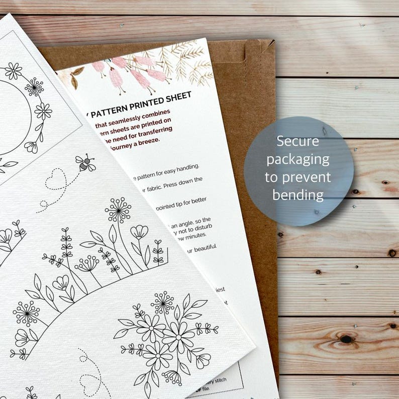 Puede incluir: Una hoja de papel blanca con patrones de bordado de l&iacute;neas negras de flores, hojas y una abeja, junto a una hoja de instrucciones con el texto 'PATTERN PRINTED SHEET' y un sobre marr&oacute;n con el texto 'Secure packaging to prevent bending'.