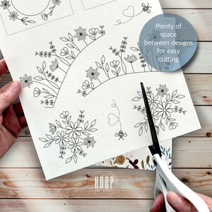 Puede incluir: Una hoja de papel blanco con ilustraciones de l&iacute;neas negras de varios arreglos florales y peque&ntilde;as abejas con trayectorias de vuelo punteadas. El texto "Plenty of space between designs for easy cutting" es visible. Unas tijeras blancas cortan el papel.