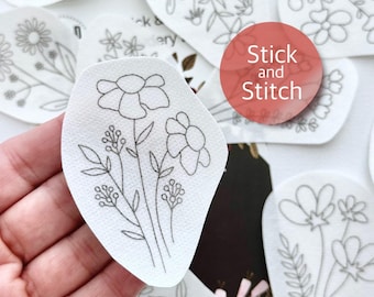 May include: A set of white fabric patches with black line drawings of flowers. The patches are labeled "Stick and Stitch".