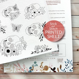 May include: A printable sheet with four black and white line drawings of a skull with flowers and butterflies. The sheet is titled "Stick and Stitch PRINTED SHEET".