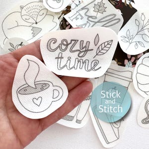 Könnte beinhalten: Ein Set weißer Bügelbilder mit verschiedenen Herbstmotiven, darunter eine Tasse Kaffee, ein gemütliches Zeitblatt und ein Kürbis. Die Patches sind mit "Stick and Stitch" beschriftet.