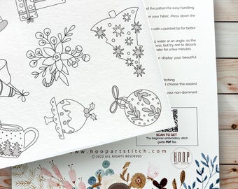 May include: A white paper sheet featuring black line art illustrations of Christmas-themed icons including wrapped gifts, a poinsettia, a tree, a pudding, and an ornament. The sheet includes printed instructions, a QR code, and the text Hoop Art Stitch.